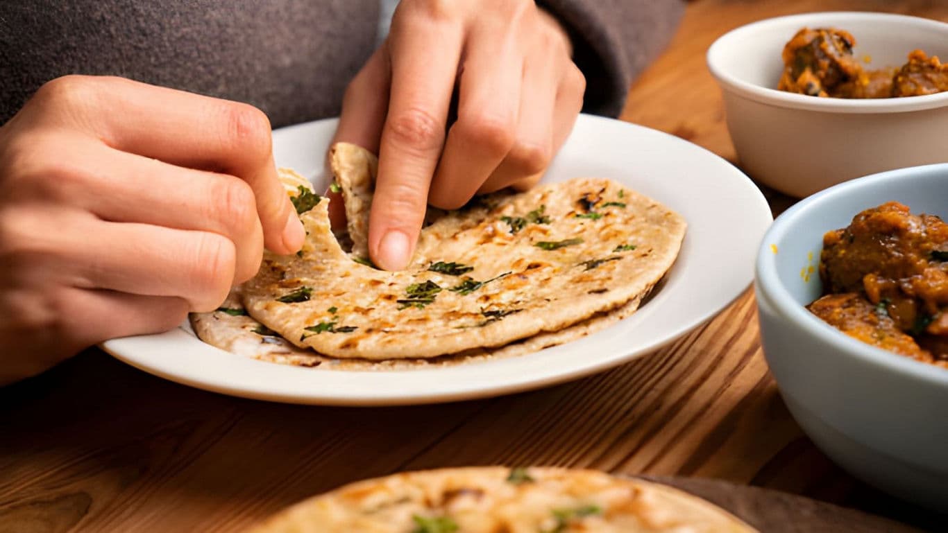 Close-up of hands eating Indian flatbread