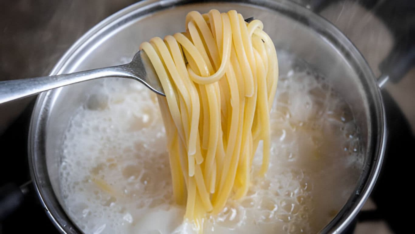 Spaghetti lifted from boiling pot with fork