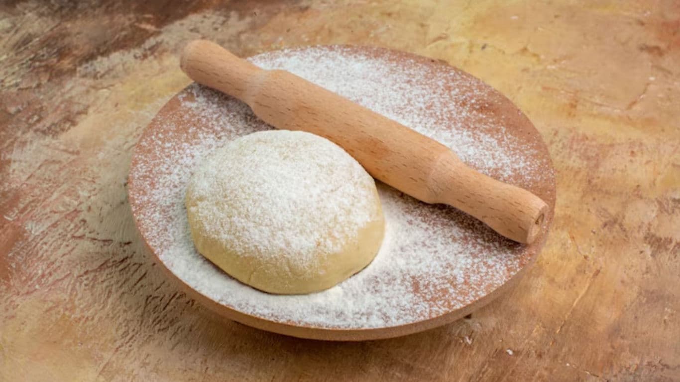 Dough ball with rolling pin on plate