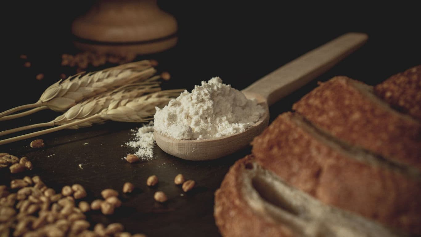 Rustic bread with wheat stalks and flour spoon