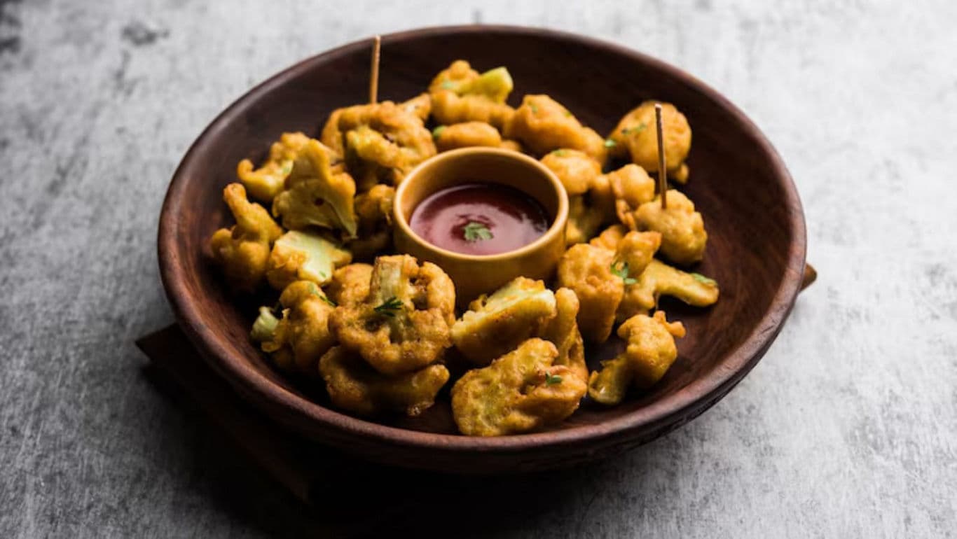 Crispy fried vegetable pakoras with dipping sauce