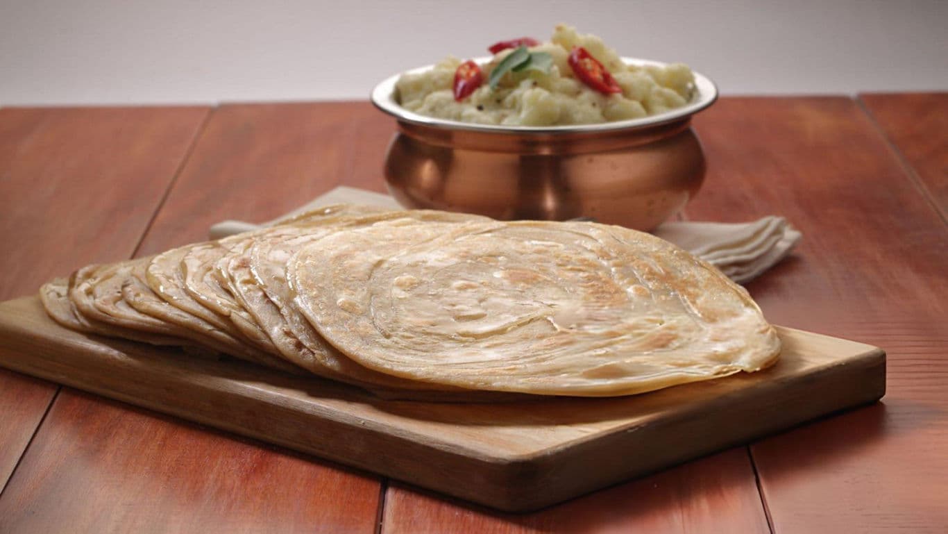 Stacked parathas with curry in copper bowl