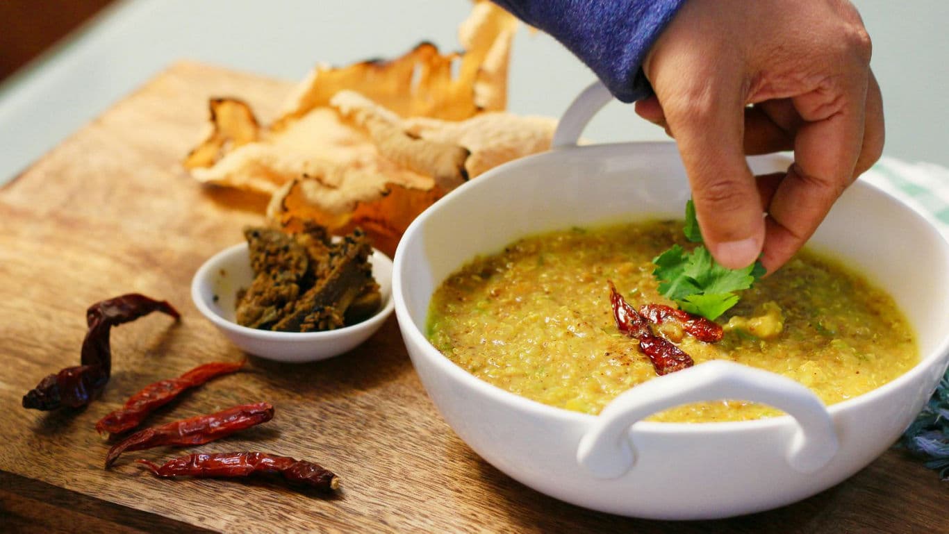 Hand garnishing spicy lentil soup bowl