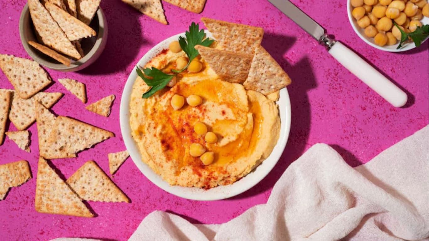 Hummus with Crackers on Pink Background