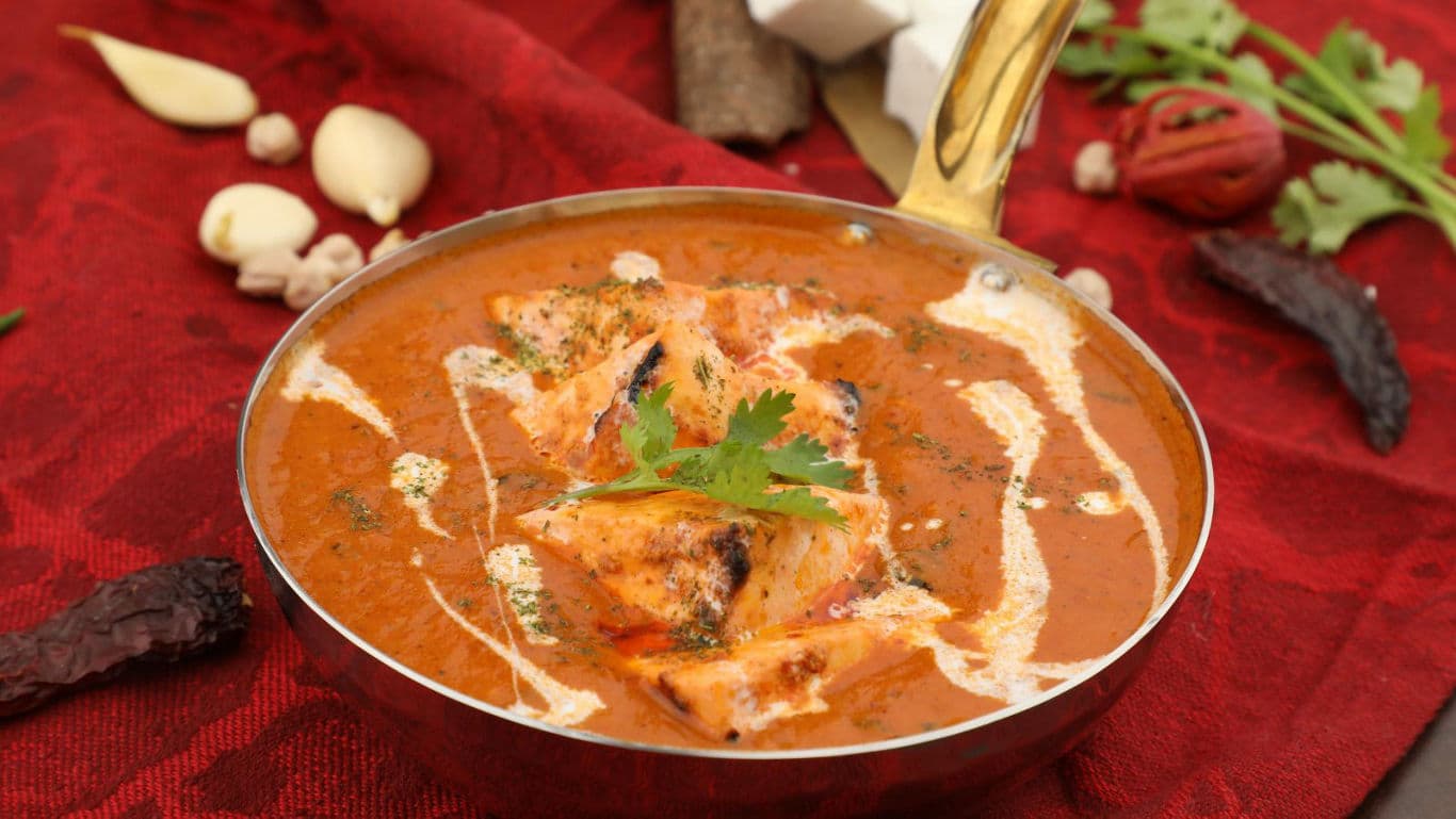 Creamy butter chicken in copper bowl