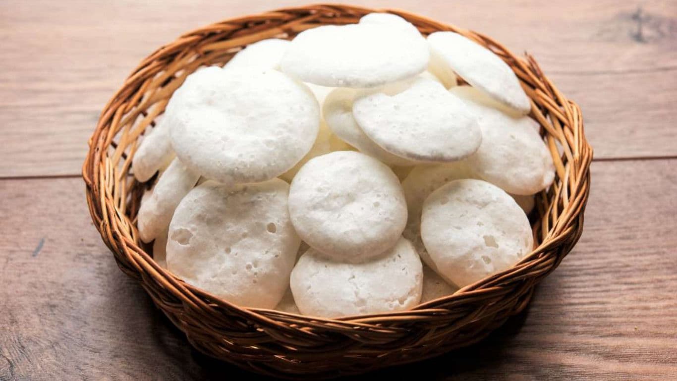 Basket of crispy rice papads on wooden table