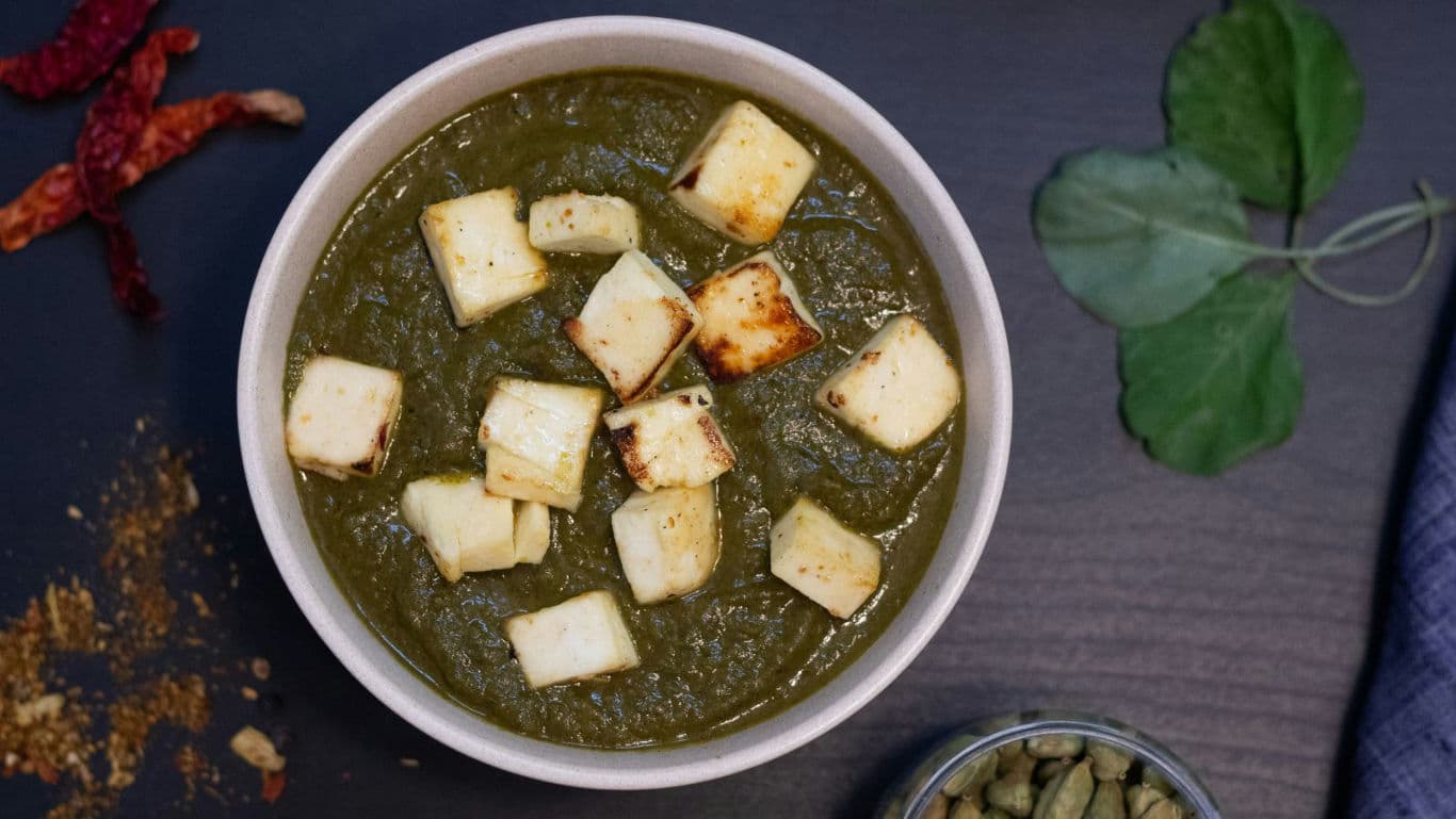 Bowl of palak paneer with fresh spices and herbs