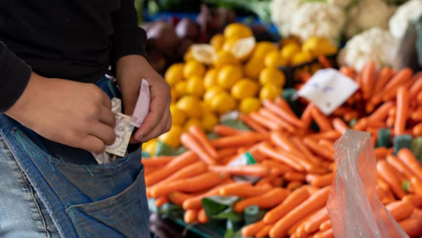 Person handling cash at vegetable market stall