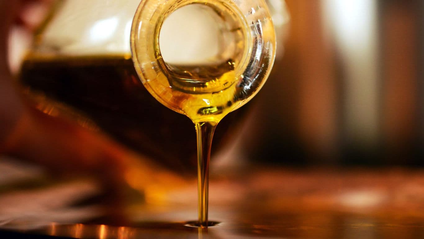 Golden syrup pouring from glass container close-up