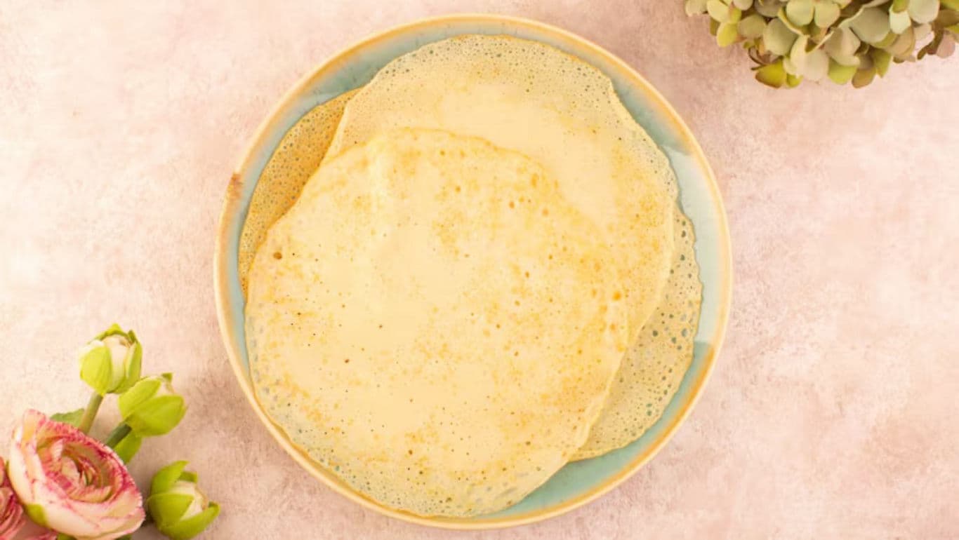 Stack of thin crepes on pastel plate with flowers