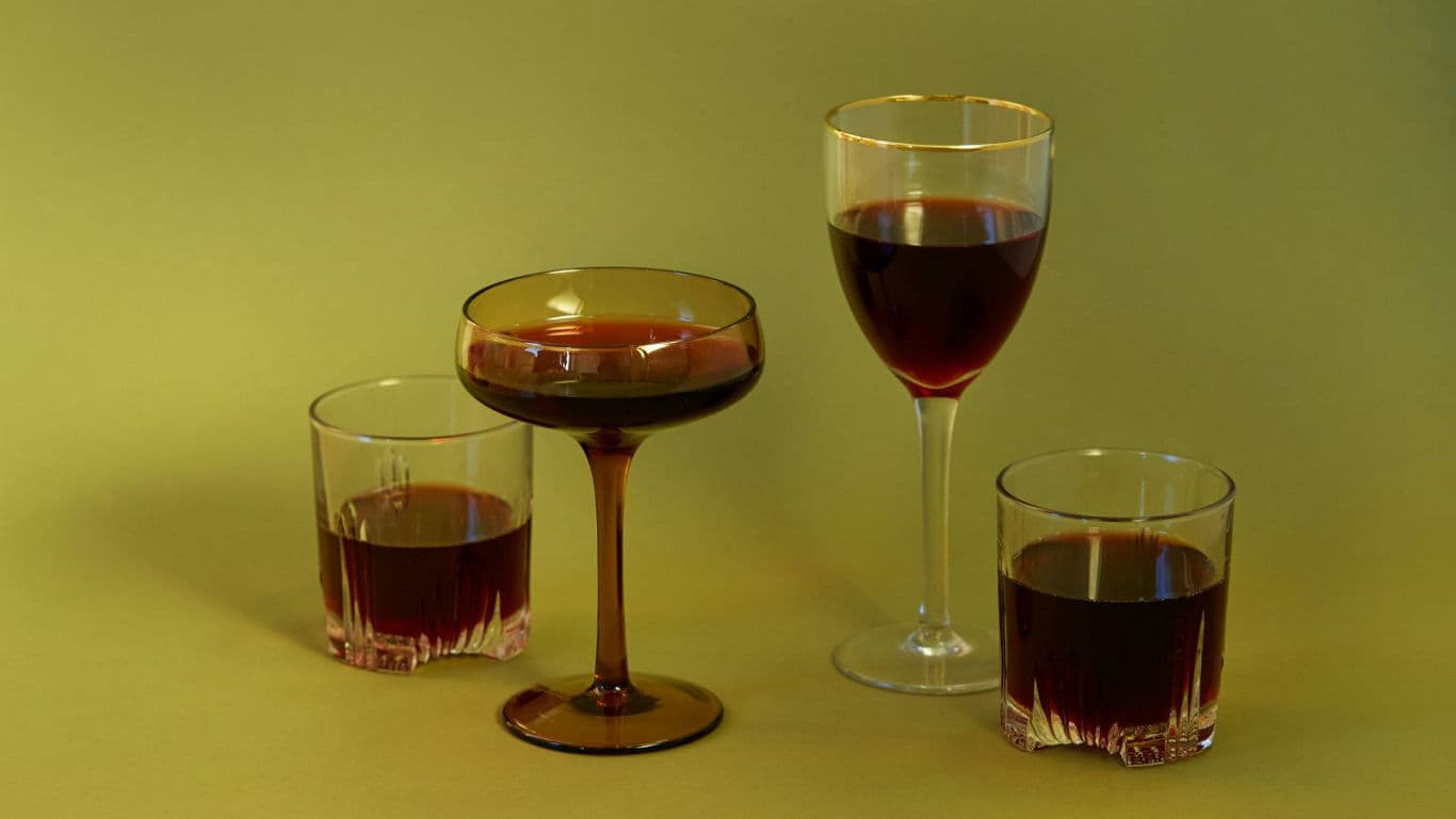 Assorted Glasses Filled With Red Beverage on Yellow