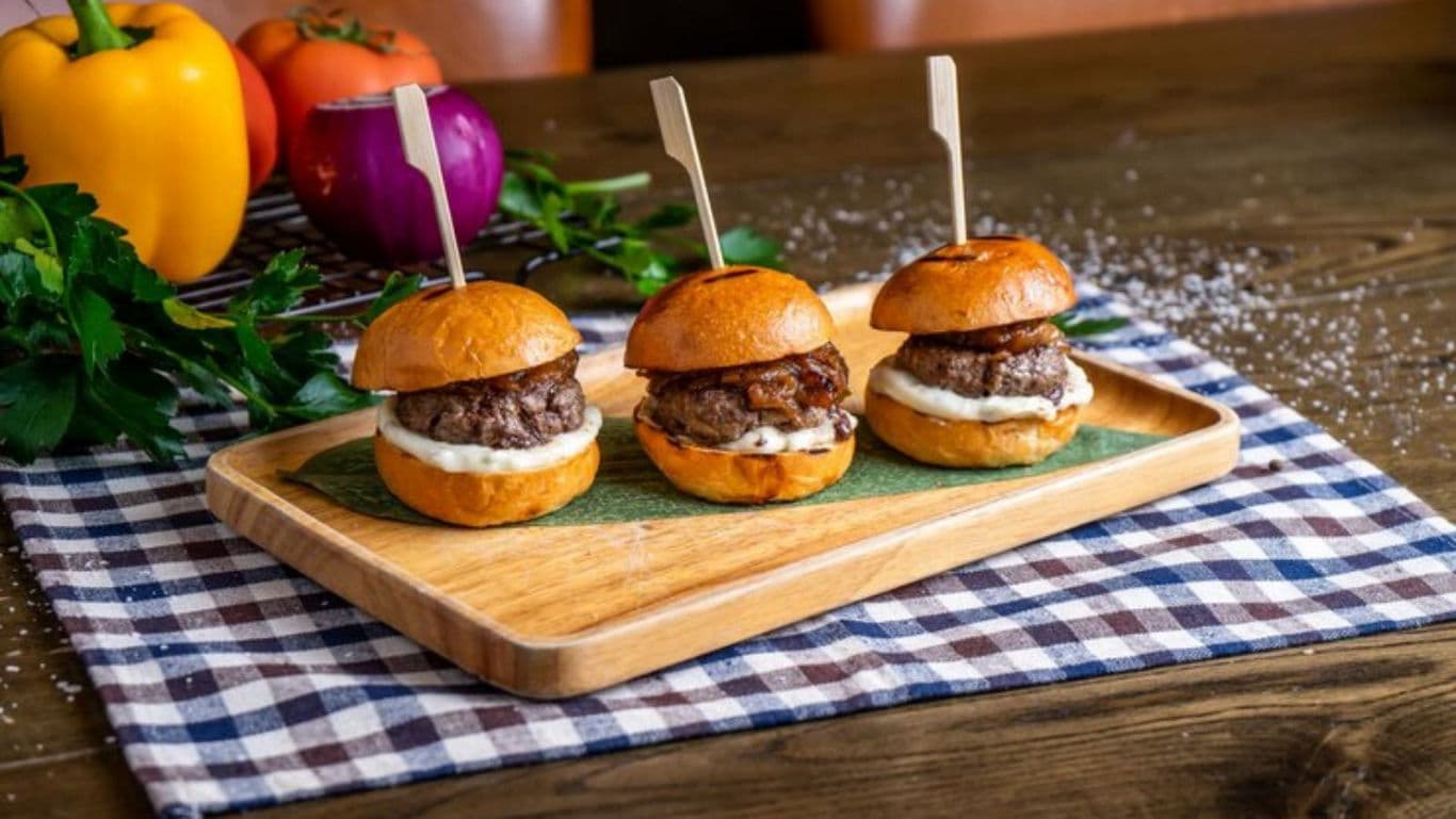 Mini burgers on wooden tray with vegetables