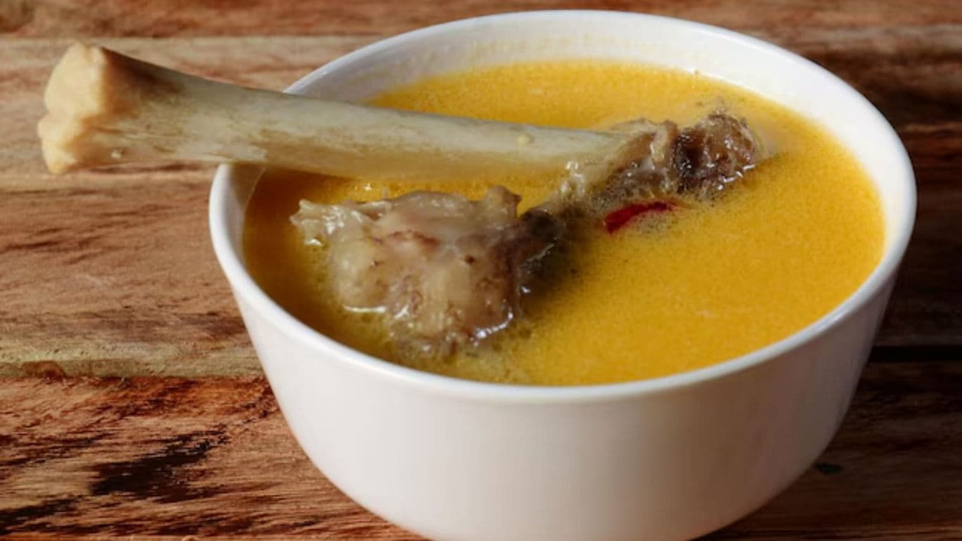 Bone broth in white bowl on wooden table